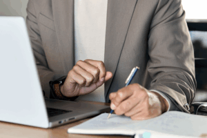 Man sitting at a desk with a laptop and notebook